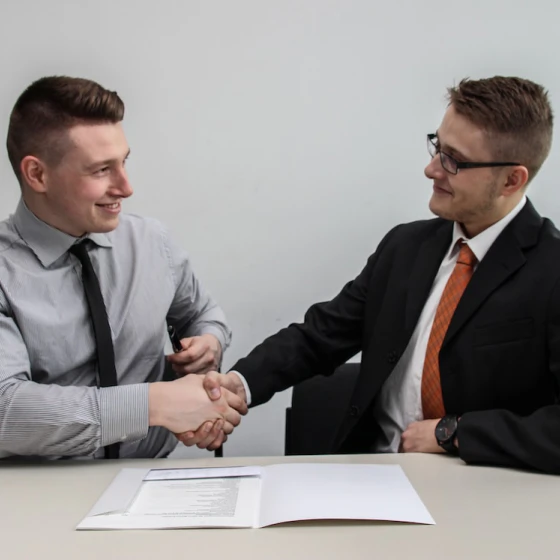 2 businessmen sitting down shaking hands