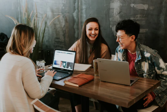 Group of people at table with laptops laughing