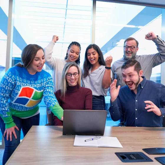 Office workers cheering while working on laptop